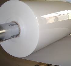 Large roll of glossy white polypropylene plastic film mounted on an industrial steel spindle shaft.