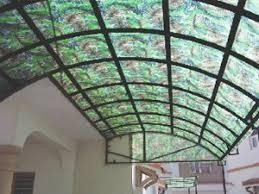 Arched metal canopy structure fitted with green leaf-patterned decorative PP sheets over an outdoor entrance area.