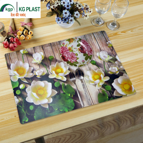 A table placemat featuring a lotus print and a floral plate setting, set on a wooden table with stemware and decorative flowers.